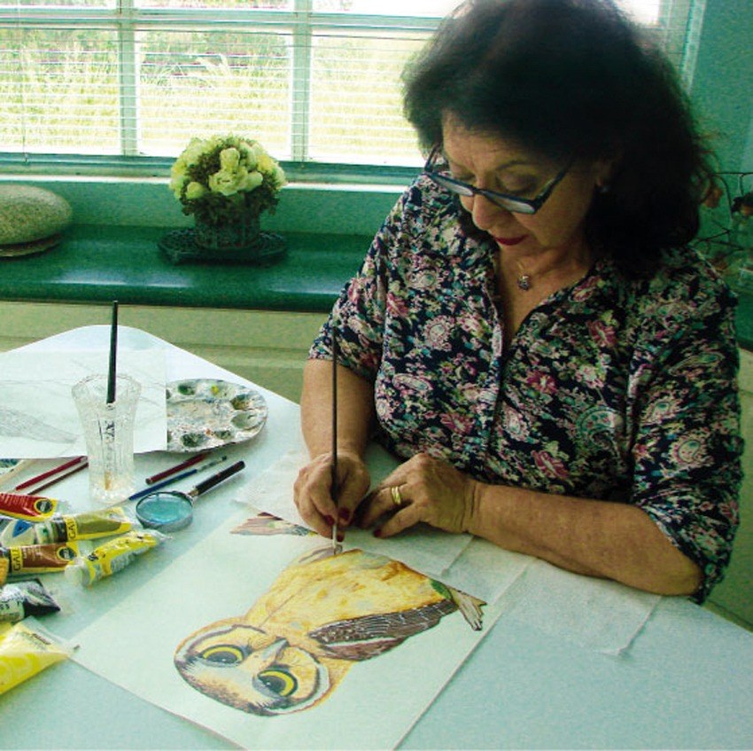 Lilly Sylva painting a Buff-fronted Owl in acrylic at her work table
